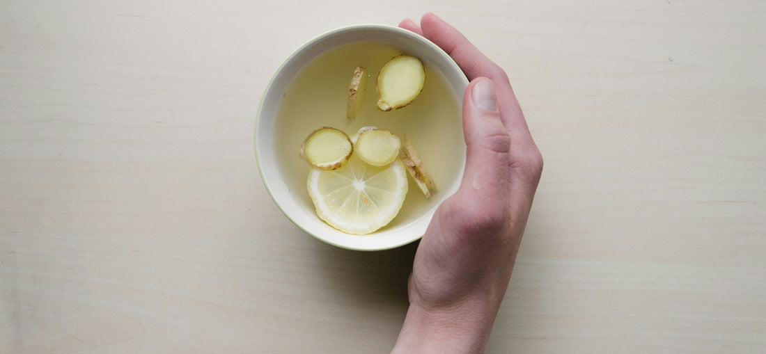 A hand holding ginger and lemon tea