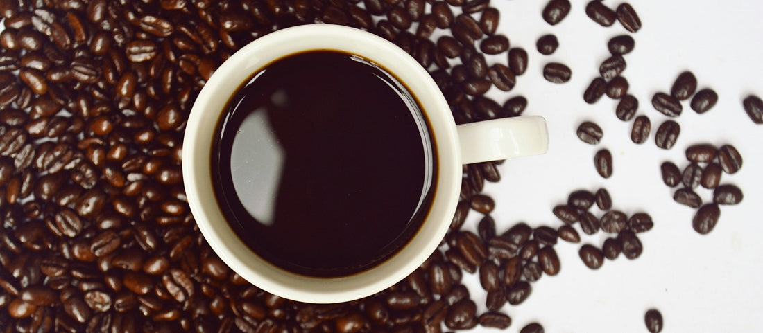 Black coffee on a background of dark roast coffee beans. Used during intermittent fasting.